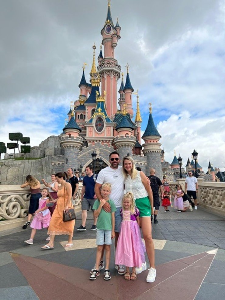 Gezin van vier poseert voor het kasteel van Disneyland Paris