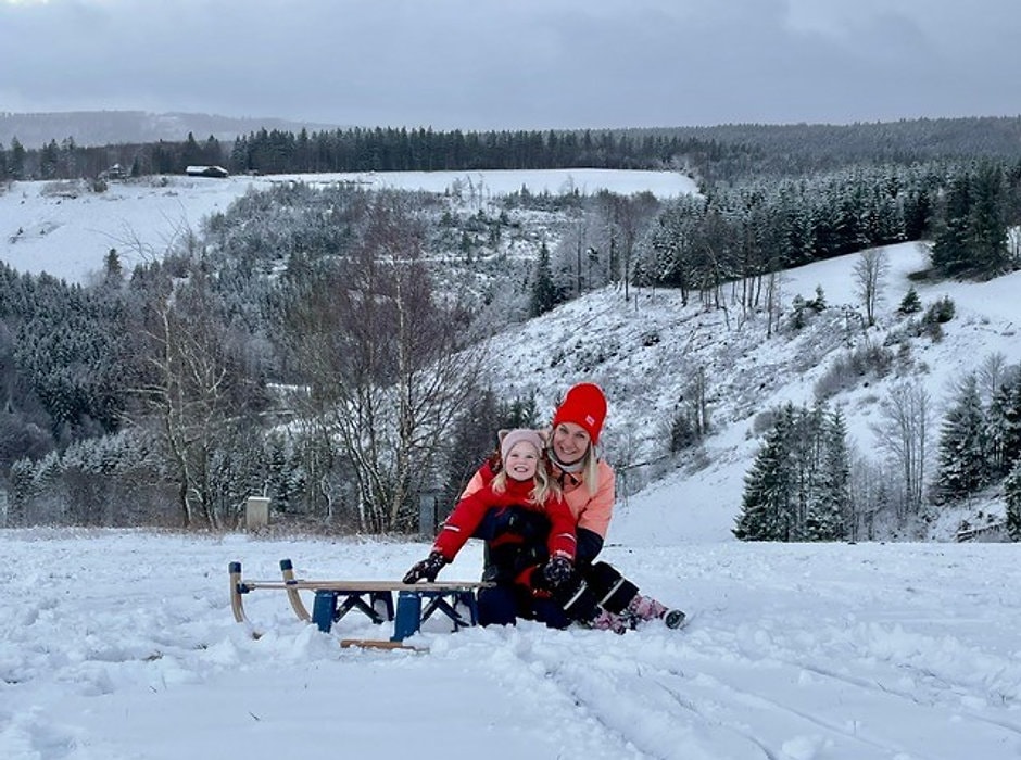 Volwassene en kind op een slee op een besneeuwde helling bij Winterberg