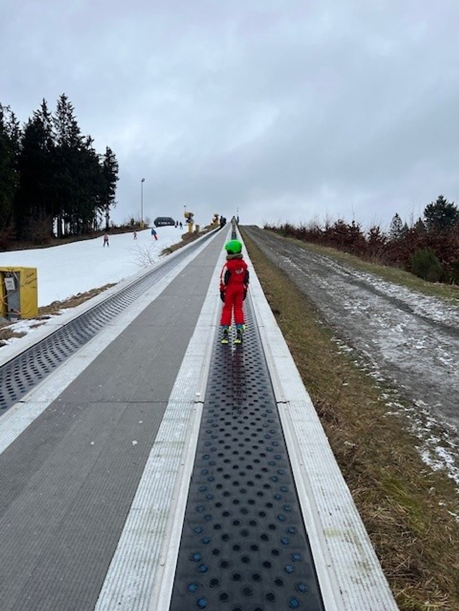 Kind op een skitravelator op een pistehelling in Winterberg
